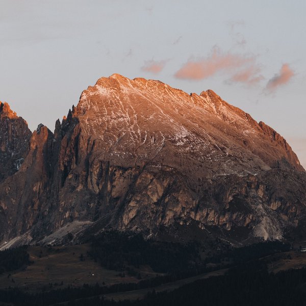 Romantischer Kurzurlaub für Verliebte – Sensoria Dolomites Alpengipfel bei Sonnenuntergang mit leichtem Schneebelag und Wald im Vordergrund