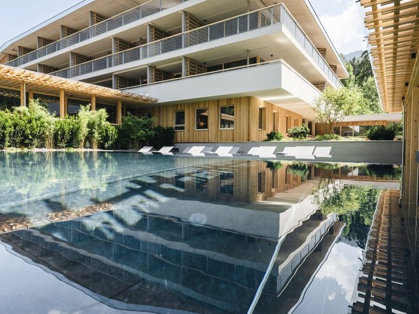 Wellness Aphrodite: Sensoria Dolomites unter den Siegern Modernes Hotel mit Pool und Sonnenliegen, Spiegelung im Wasser