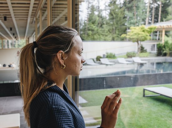 Wellnesshotel auf der Seiser Alm – Luxus für die Seele Frau blickt aus Fenster in einen Garten mit Pool in einem Spa