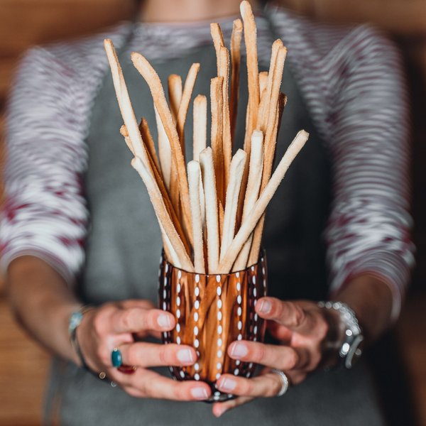 Nachhaltiges Handeln im Sensoria Dolomites Person hält ein Glas mit langen knusprigen Grissini-Stangen