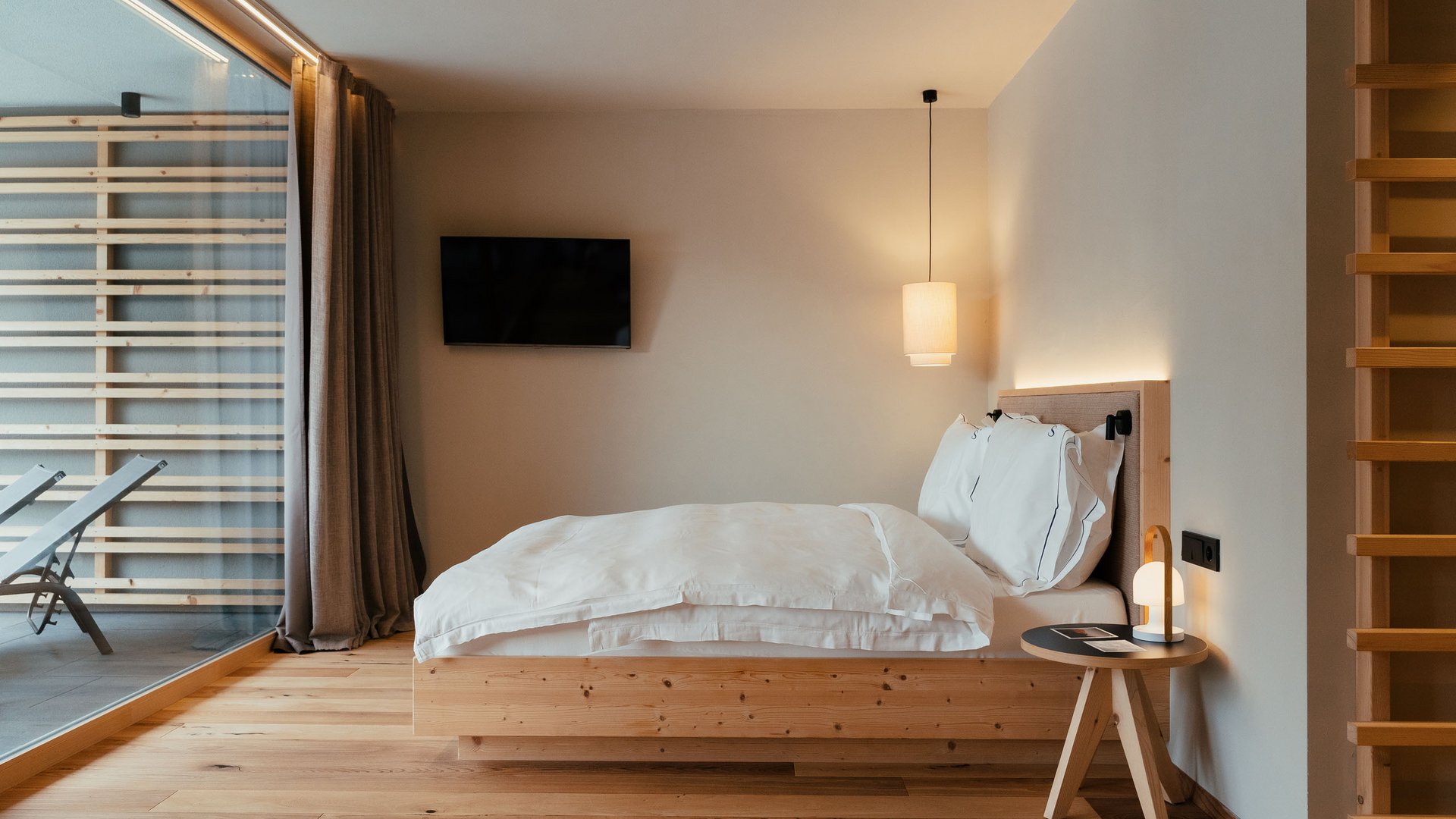Nachhaltiges Handeln im Sensoria Dolomites Modernes Schlafzimmer mit Holzdetails, Doppelbett und großem Fenster zur Terrasse
