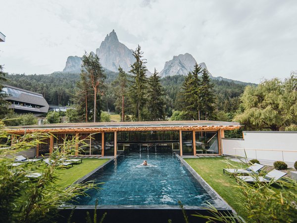 Wellness Aphrodite: Sensoria Dolomites unter den Siegern Frau schwimmt im Außenpool mit Bergblick und Grünflächen
