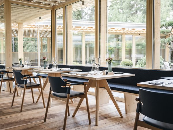 Wellness Aphrodite: Sensoria Dolomites unter den Siegern Modernes Restaurant mit Holzmöbeln und großen Fenstern mit Gartenblick