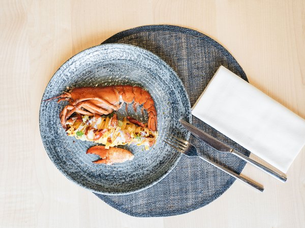 Wellness Aphrodite: Sensoria Dolomites unter den Siegern Gourmet-Hummergericht auf blauem Teller mit Besteck und Serviette