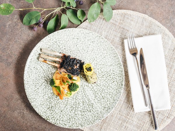 Wellness Aphrodite: Sensoria Dolomites unter den Siegern Gourmetgericht mit Lammkoteletts, Gemüse und Soße auf dekorativem Teller