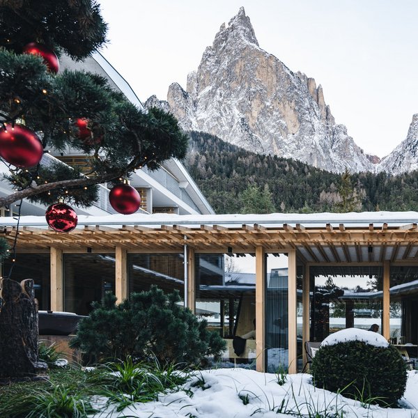 Sensoria Dolomites: Wellnesshotel in den Dolomiten Schneebedecktes Hotel mit Weihnachtsbaumschmuck vor schneebedeckten Bergen