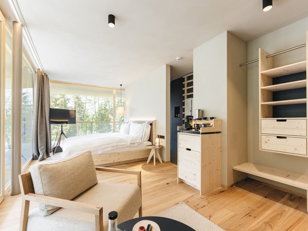Wellness Aphrodite: Sensoria Dolomites unter den Siegern Modernes Hotelzimmer mit Holzfußboden und großem Fenster mit Waldblick
