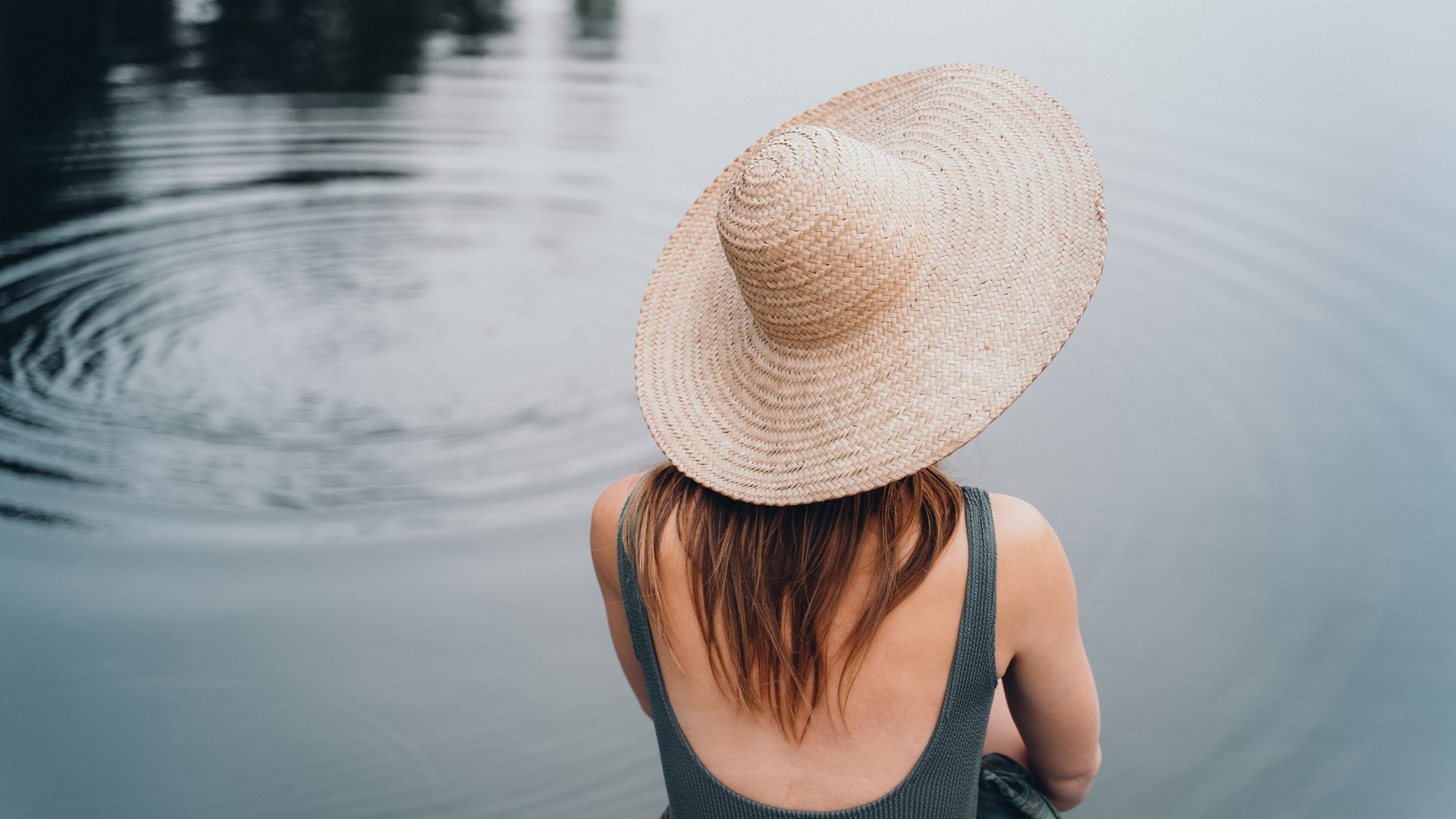 Die Dolomiten – Skiurlaub und so viel mehr Person mit Strohhut sitzt entspannt am ruhigen See
