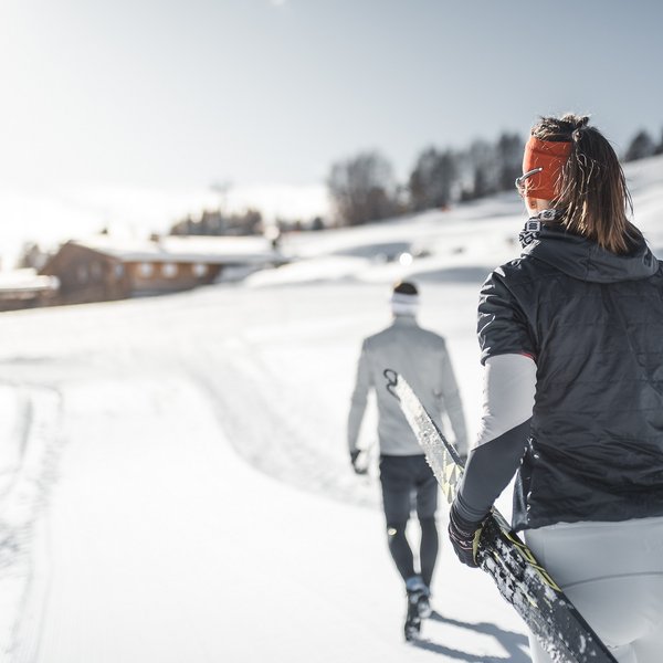 Seiser Alm: Skiurlaub de luxe Zwei Skilangläufer auf verschneiter Strecke bei sonnigem Wetter