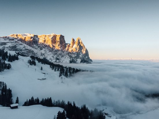 Seiser Alm: Skiurlaub de luxe Schneebedeckte Berge bei Sonnenuntergang mit Nebel im Tal