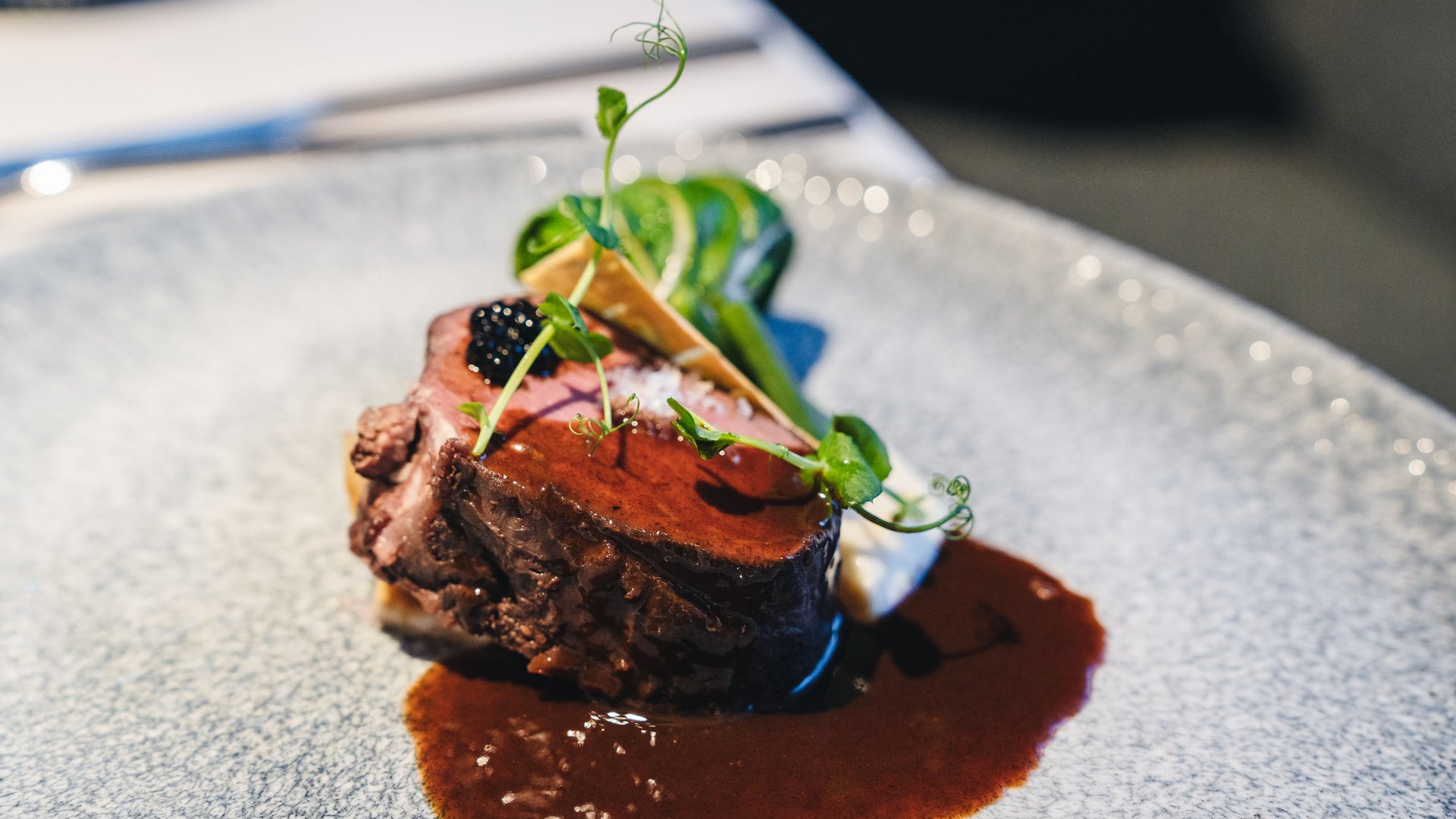 Nachhaltiges Handeln im Sensoria Dolomites Fein angerichtetes Stück Rinderfilet mit Sauce und grünem Gemüse