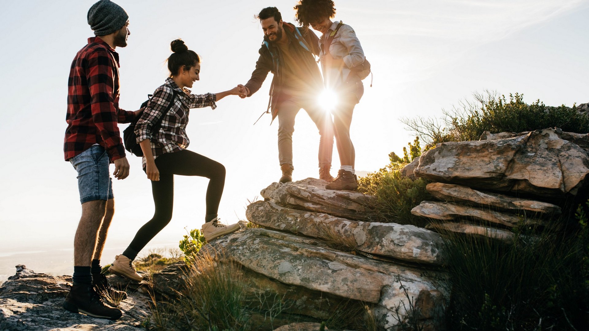 Größte Hochalm Europas – ein Kraftplatz mit Seele Freunde helfen sich beim Klettern auf felsigem Gelände bei Sonnenuntergang