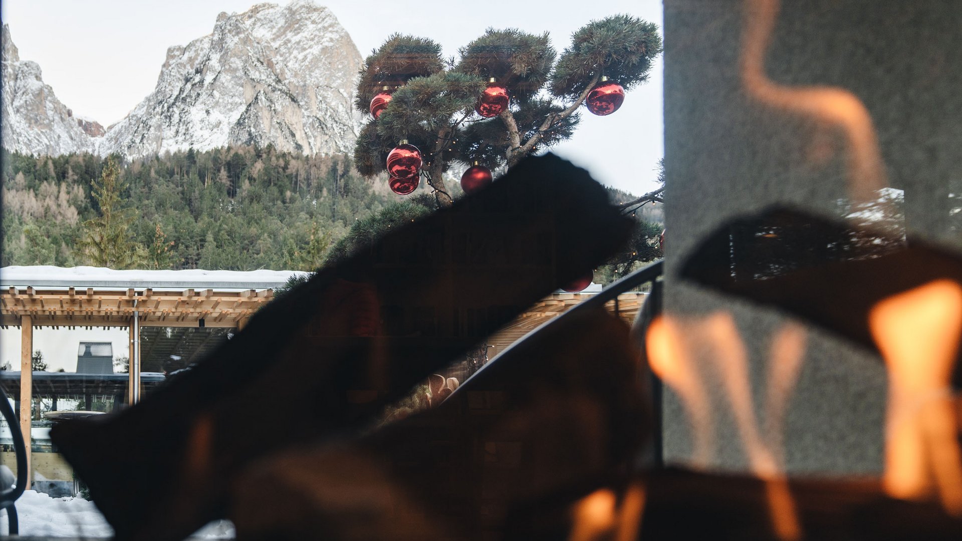 Sensoria Dolomites: Wellnesshotel in den Dolomiten Blick auf verschneite Berge und Weihnachtsbaum mit roten Kugeln durch ein Fenster