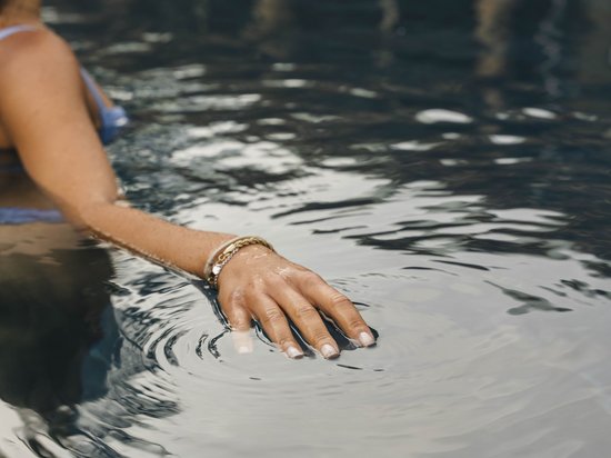 Größte Hochalm Europas – ein Kraftplatz mit Seele Frau mit Armband im Wasser berührt die Wasseroberfläche im Pool