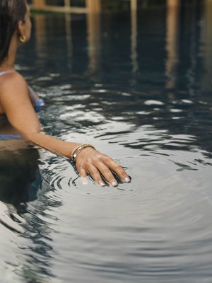 Luxus für die Seele im Kurzurlaub in Südtirol Frau mit Armband im Wasser berührt die Wasseroberfläche im Pool