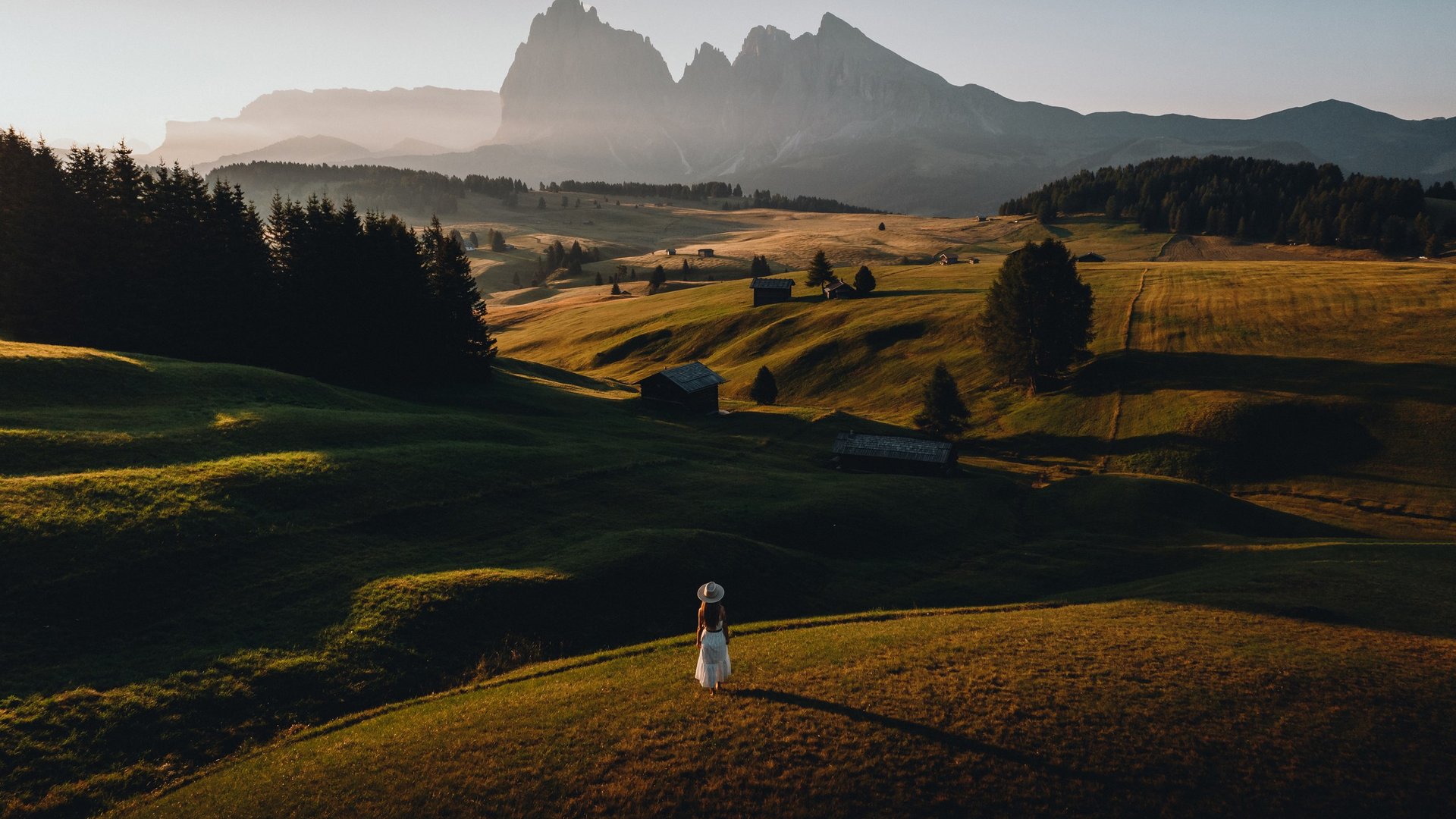 Die Dolomiten – Skiurlaub und so viel mehr Frau im weißen Kleid auf einer Wiese mit Bergpanorama im Hintergrund