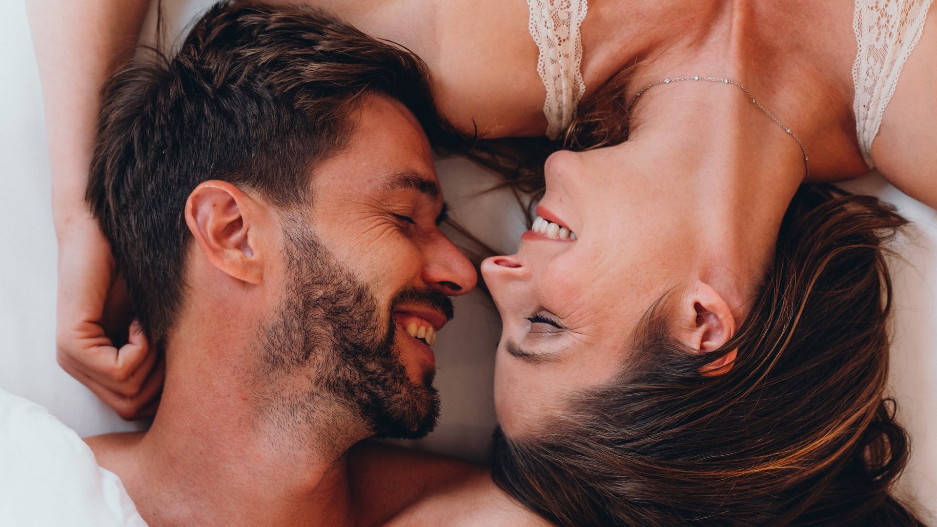 Kostbare Augenblicke in Ihrem Romantikhotel in den Dolomiten Glückliches Paar liegt nebeneinander im Bett und lächelt sich an