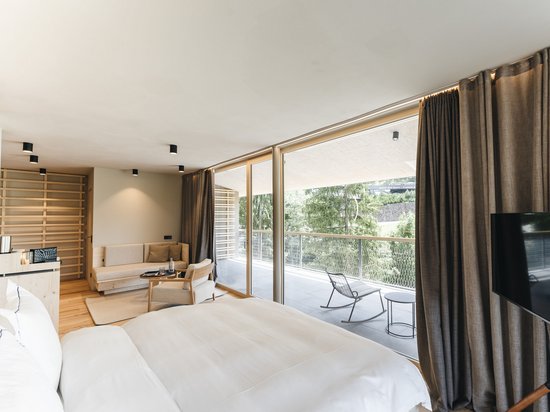 Ort der Kraft – Ihr Lieblingszimmer Modernes Hotelzimmer mit Bett, Sitzbereich und großem Balkon mit Naturblick