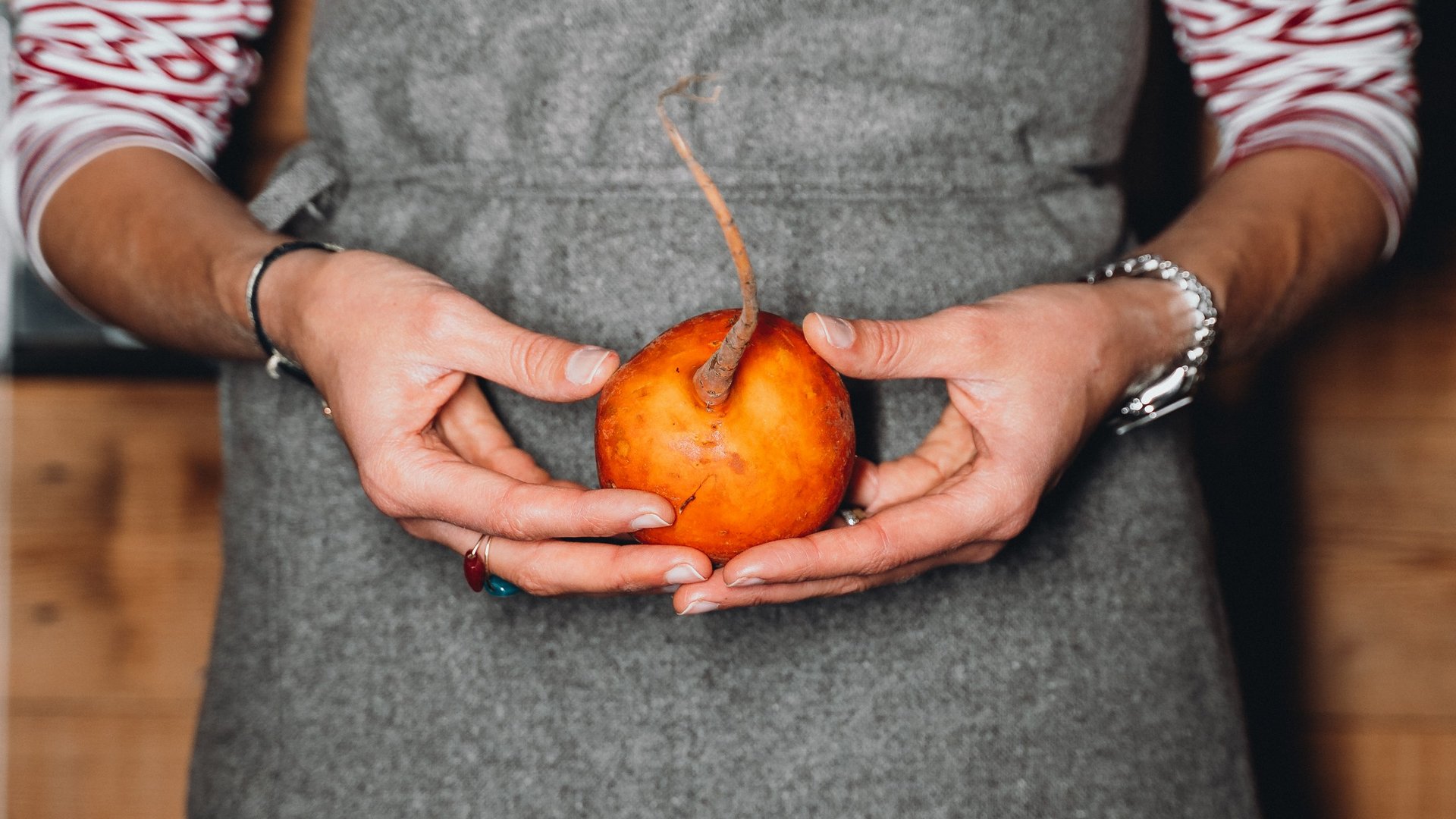 Unser Genussmarkt – perfekt für Ihr Romantikwochenende Person hält eine orangefarbene Rübe mit langem Stiel in den Händen