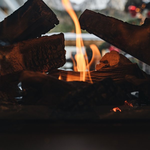 Sensoria Dolomites: Wellnesshotel in den Dolomiten Flammen lodern in einem Holzofen mit Bergen im Hintergrund