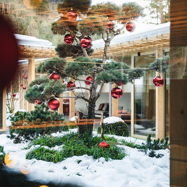 Sensoria Dolomites: Wellnesshotel in den Dolomiten Weihnachtsbaum draußen mit roten Kugeln und Schnee umgeben