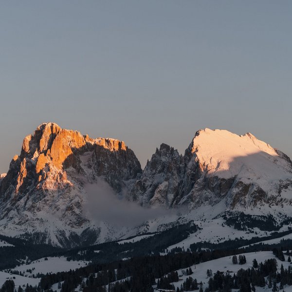 Seiser Alm: Skiurlaub de luxe Schneebedeckte Berge bei Sonnenuntergang mit oranger Beleuchtung