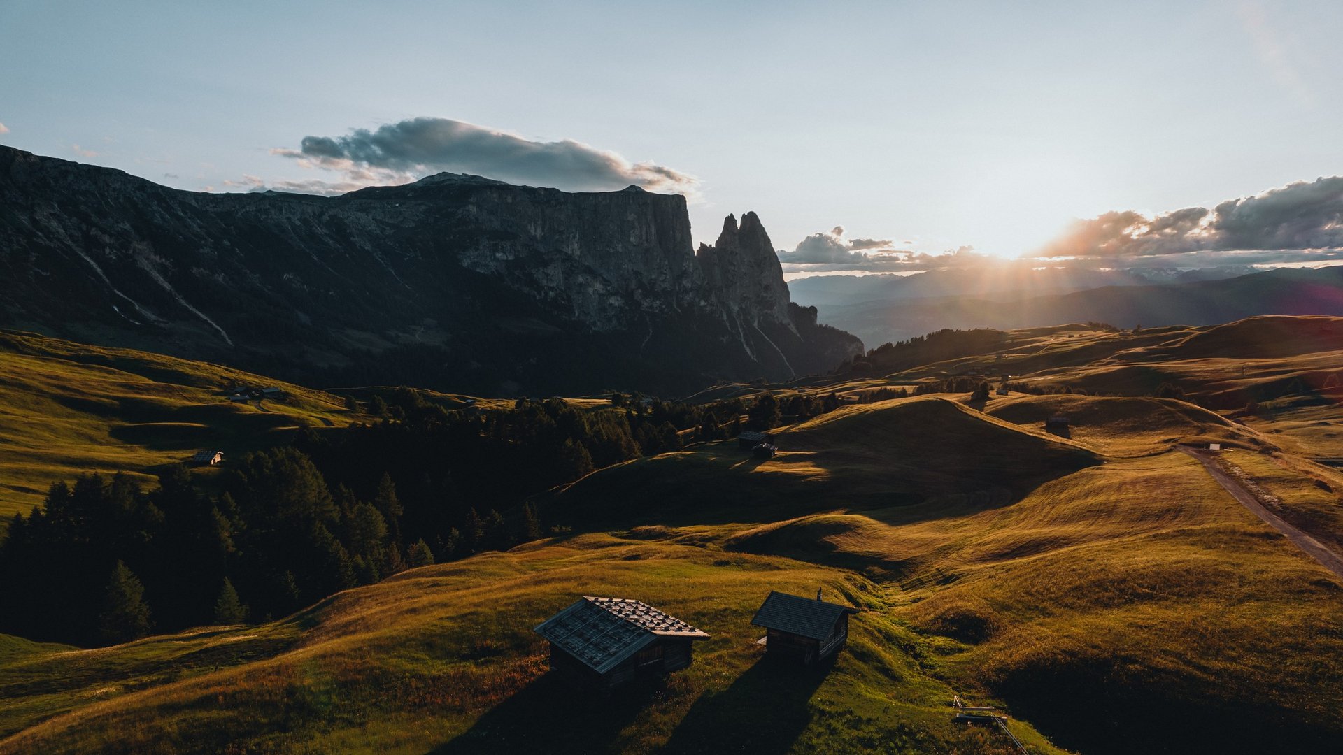 Urlaub in den Dolomiten – Urlaub im Sensoria Dolomites Sonnenuntergang über grünen Hügeln und Bergcharakter im Hintergrund