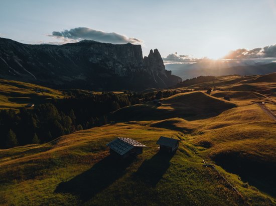 Mehr als ein Hotel im Naturpark Schlern-Rosengarten Sonnenuntergang über grünen Hügeln und Bergcharakter im Hintergrund