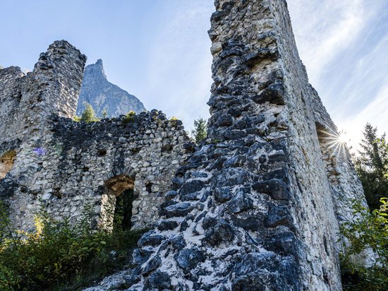 Die Dolomiten – Skiurlaub und so viel mehr Ruine einer alten Steinburg vor Berg und blauem Himmel im Sonnenschein