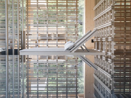 Inclusive services – last-minute South Tyrol holidays Modern wooden architecture with lounge chair and reflection in water