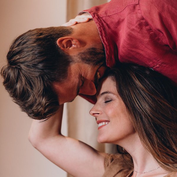 Romantischer Kurzurlaub für Verliebte – Sensoria Dolomites Paar zeigt Zuneigung mit Kuss auf der Stirn und lächelndem Gesicht