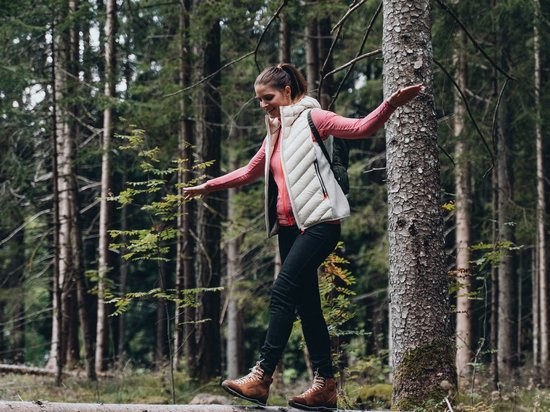 Luxus für die Seele im Kurzurlaub in Südtirol Frau balanciert auf liegendem Baumstamm im Wald