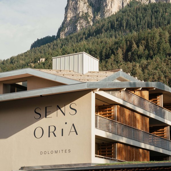 Romantischer Kurzurlaub für Verliebte – Sensoria Dolomites Hotel Sensoria Dolomites vor bewaldeten Bergen und Felsformationen