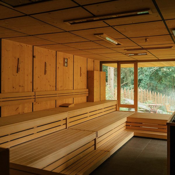 Von Wanderungen auf der Seiser Alm in die Spa Area Moderner Saunaraum mit Holzbänken und Ausblick ins Grüne