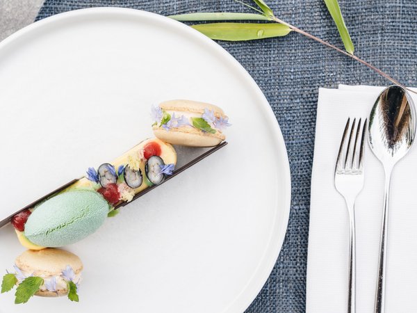 Wellness Aphrodite: Sensoria Dolomites unter den Siegern Fein dekoriertes Dessert mit grünem Eis und Macarons auf weißem Teller