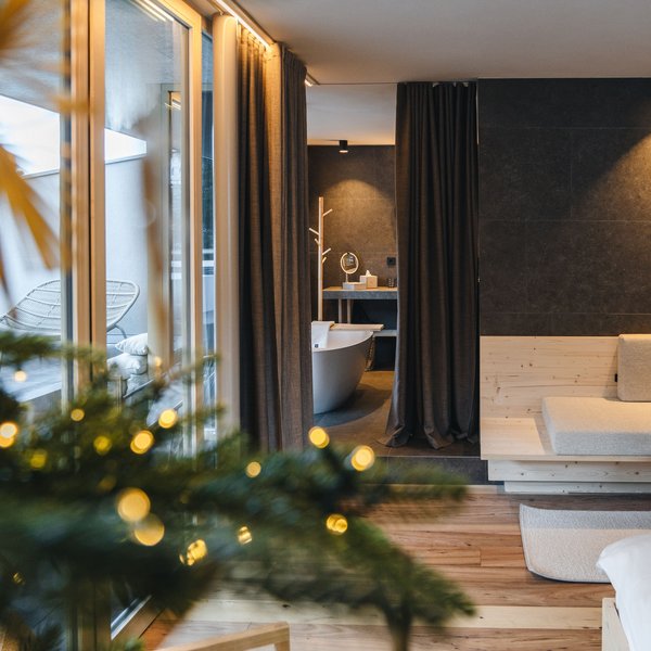 Sensoria Dolomites: Wellnesshotel in den Dolomiten Gemütliches Zimmer mit Holzfußboden und freistehender Badewanne hinter Vorhängen