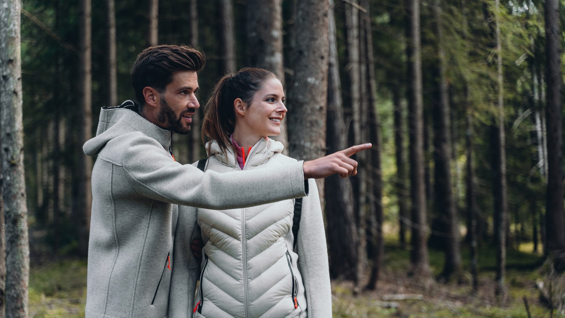 Aktivurlaub in Südtirol – bereit für Natur pur? Paar beim Wandern zeigt in einen Wald