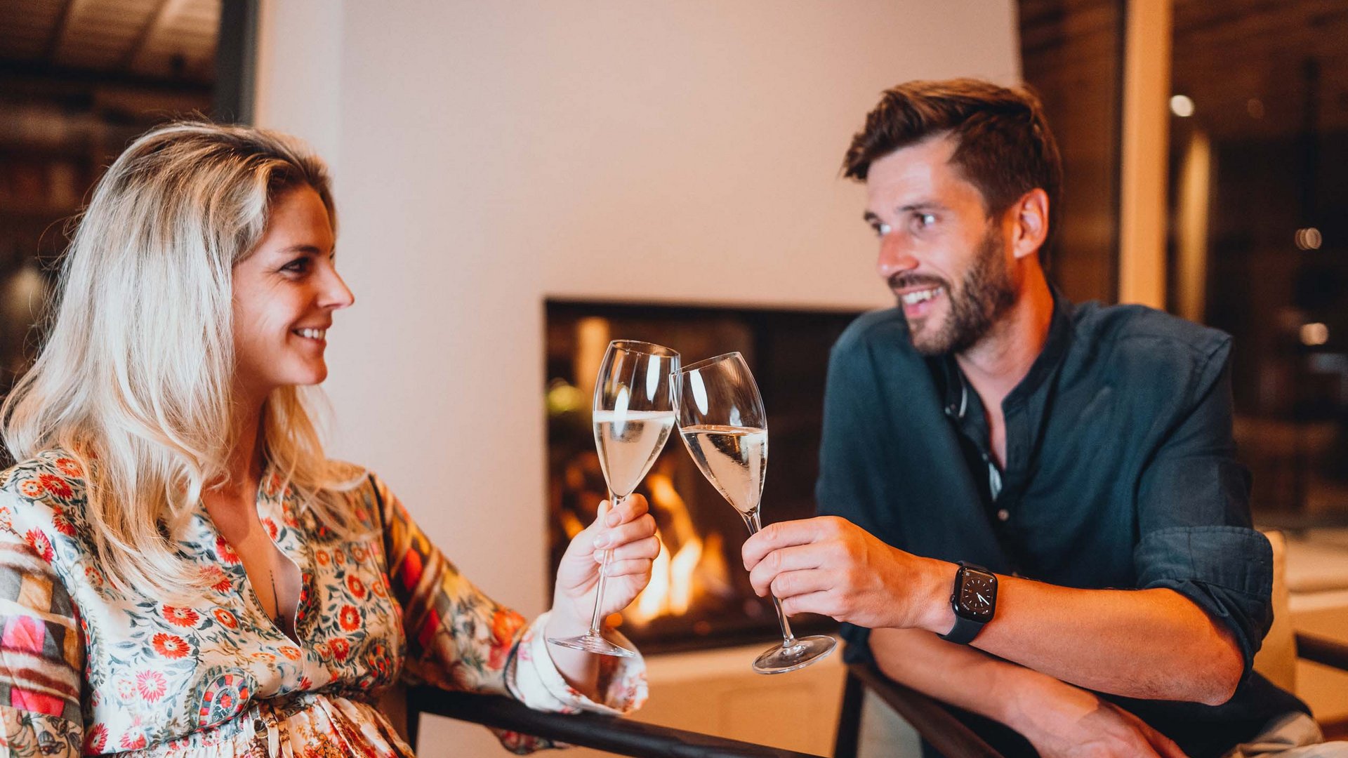 Silvester in den Bergen Paar stößt mit Sektgläsern vor Kamin an