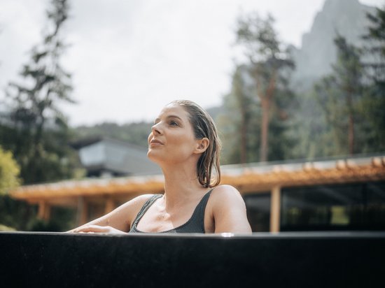 Größte Hochalm Europas – ein Kraftplatz mit Seele Frau entspannt im Außenwhirlpool mit Wald- und Bergblick