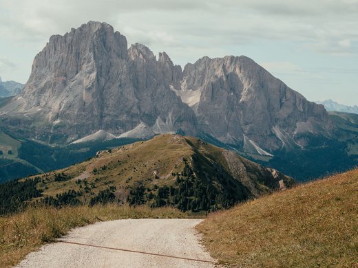 Inclusive services – last-minute South Tyrol holidays Hiking trail with mountain backdrop under a cloudy sky
