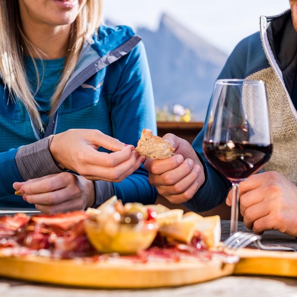 Seiser Alm: Skiurlaub de luxe Pärchen beim Essen von Brot und Antipasti mit Wein im Freien