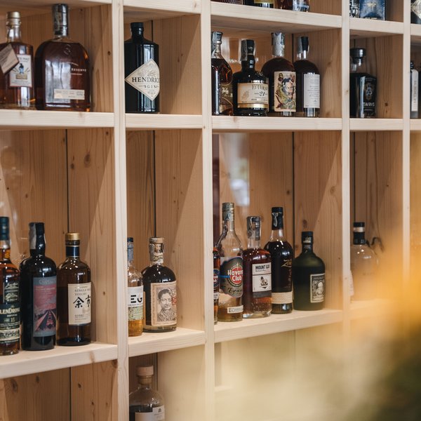 Genussurlaub in Südtirol – Sensoria Dolomites Verschiedene Spirituosenflaschen in einem hölzernen Regal