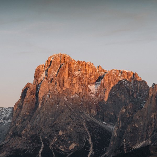 Aktivurlaub in Südtirol – bereit für Natur pur? Bergspitzen im warmen Licht des Sonnenuntergangs mit leichtem Schneebelag