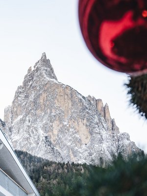 Sensoria Dolomites: Wellnesshotel in den Dolomiten Schneebedeckter Berg mit modernem Gebäude und rotem Weihnachtsornament
