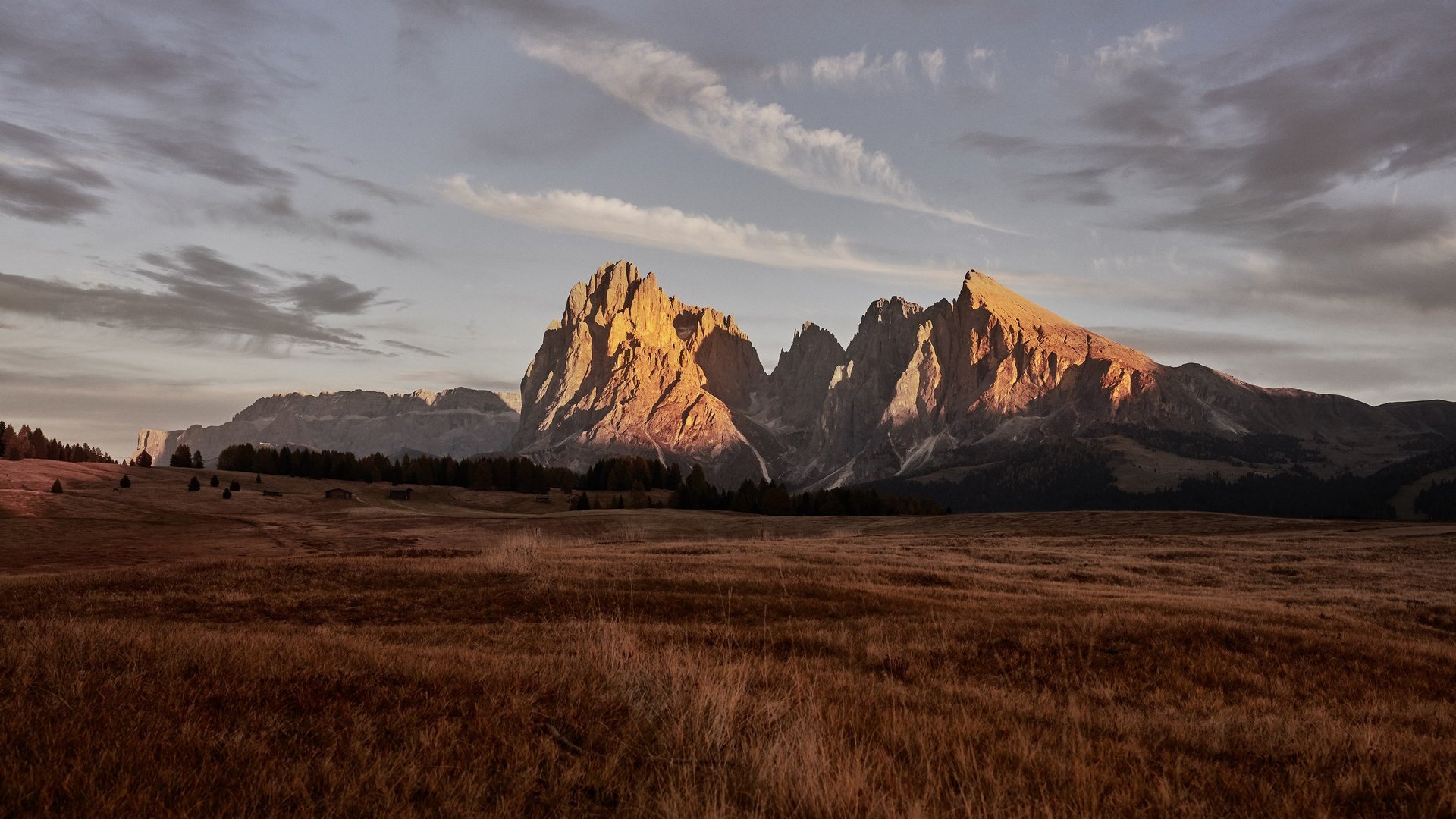 Mehr als ein Hotel auf der Seiser Alm: Sensoria Dolomites Berglandschaft bei Sonnenaufgang mit leuchtenden Gipfeln und weitem Tal
