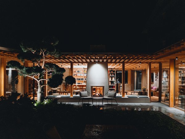 Wellness Aphrodite: Sensoria Dolomites unter den Siegern Modernes Holzhaus mit beleuchtetem Kamin und Garten bei Nacht