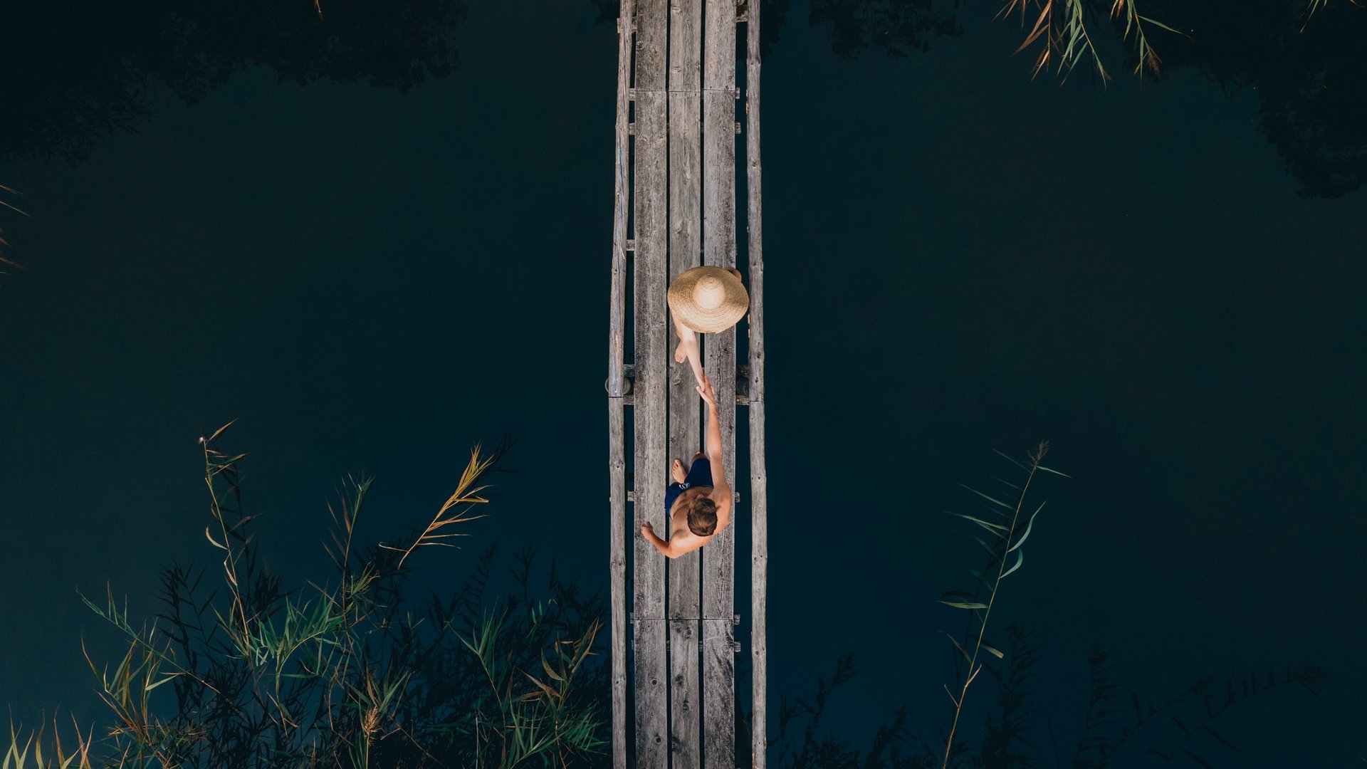 Die Dolomiten – Skiurlaub und so viel mehr Zwei Personen schütteln Hände auf einem Holzsteg über dunklem Wasser