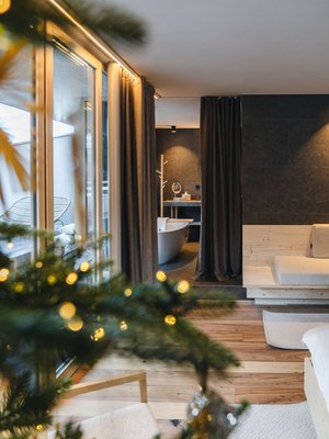 Sensoria Dolomites: Wellnesshotel in den Dolomiten Gemütlicher Raum mit Holzfußboden, Sofa, und Badewanne im hinteren Bereich