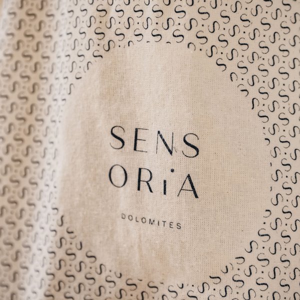 Romantischer Kurzurlaub für Verliebte – Sensoria Dolomites Logo Sensoria Dolomites auf einem Stoff mit kleinen S-Mustern