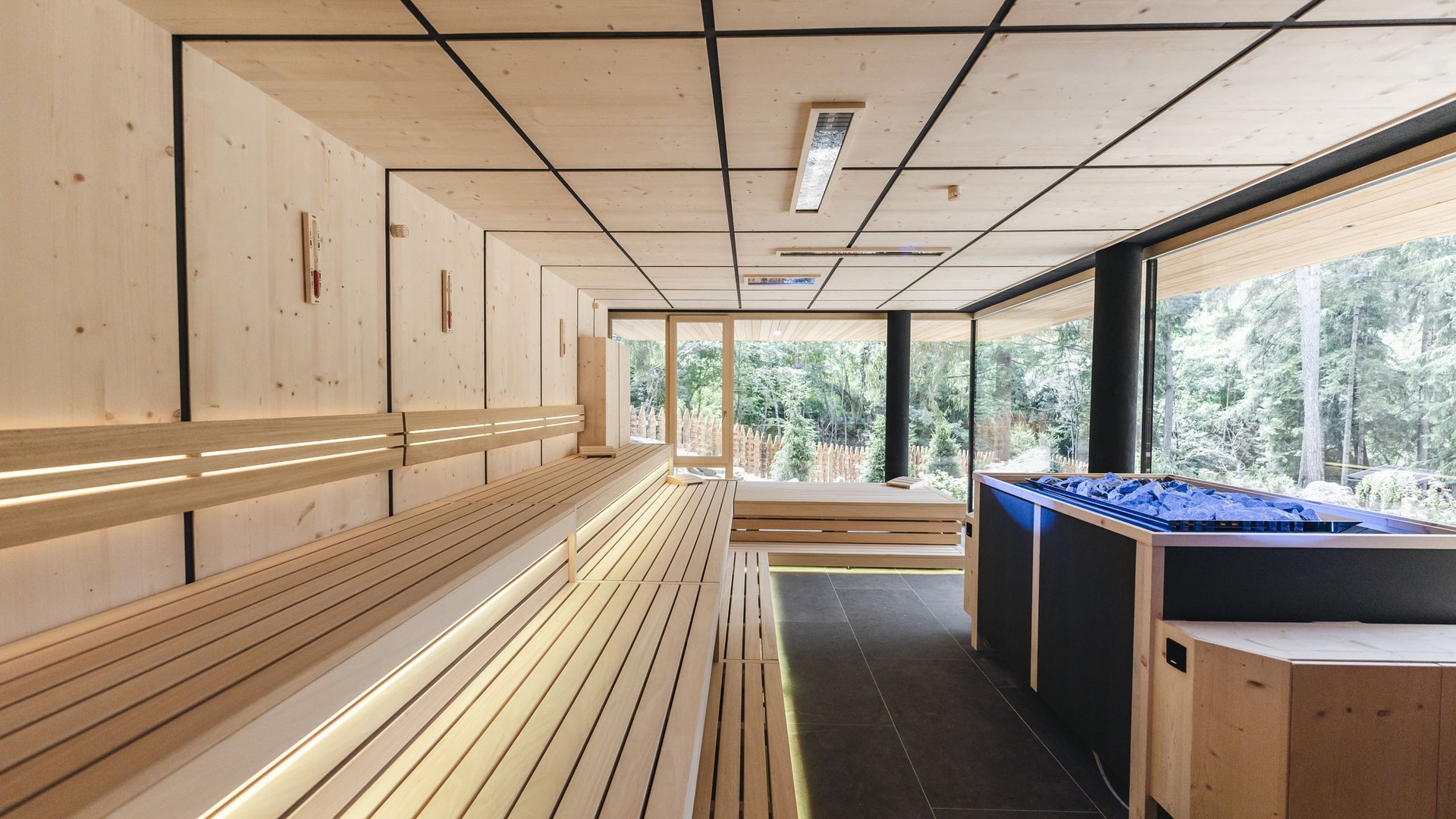 Von Wanderungen auf der Seiser Alm in die Spa Area Moderne Sauna mit Holzbänken und Blick ins Grüne